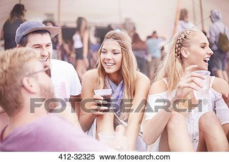 Stock Photography - Young friends hanging out drinking at music festival. Fotosearch