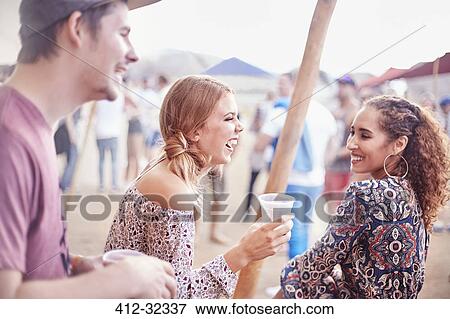 Young friends laughing and drinking at music festival View Large Photo Image Stock Photo - Young friends laughing and drinking at music festival. Fotosearch
