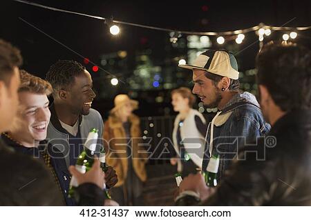 Young friends talking and drinking at rooftop party View Large Photo Image Stock Photo - Young friends talking and drinking at rooftop party. Fotosearch