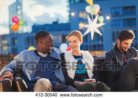 Young man and woman flirting at nighttime rooftop party View Large Photo Image Stock Image - Young man and woman flirting at nighttime rooftop party. Fotosearch