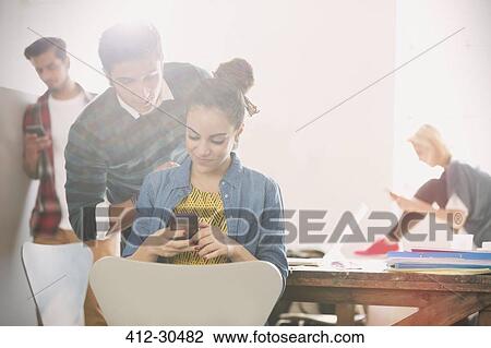 Young man and woman texting with cell phone in office View Large Photo Image Stock Image - Young man and woman texting with cell phone in office. Fotosearch