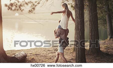 Young man carrying woman on shoulders at lakeside View Large Photo Image Stock Photograph - Young man carrying woman on shoulders at lakeside. Fotosearch