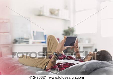 Young man using digital tablet on bed View Large Photo Image Stock Image - Young man using digital tablet on bed. Fotosearch