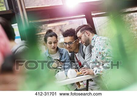 Young men and women texting with cell phone in cafeteria View Large Photo Image Stock Image - Young men and women texting with cell phone in cafeteria. Fotosearch