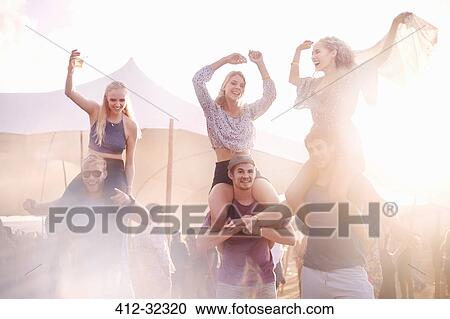 Young men carrying playful women on shoulders at music festival View Large Photo Image Stock Image - Young men carrying playful women on shoulders at music festival. Fotosearch