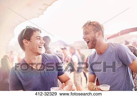 Stock Photo - Young men drinking and laughing at music festival. Fotosearch