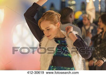Young woman dancing at nighttime rooftop party View Large Photo Image Stock Photo - Young woman dancing at nighttime rooftop party. Fotosearch