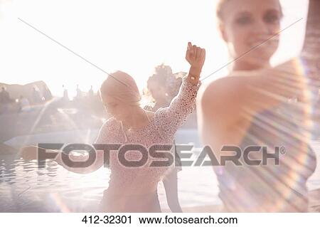 Young woman dancing at sunny poolside party View Large Photo Image Stock Image - Young woman dancing at sunny poolside party. Fotosearch