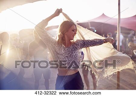 Stock Image - Young woman dancing with scarf at music festival. Fotosearch