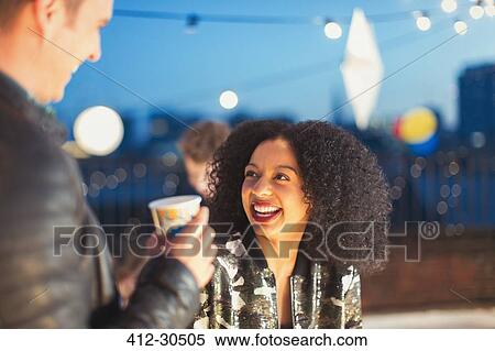 Stock Photography - Young woman enjoying rooftop party. Fotosearch
