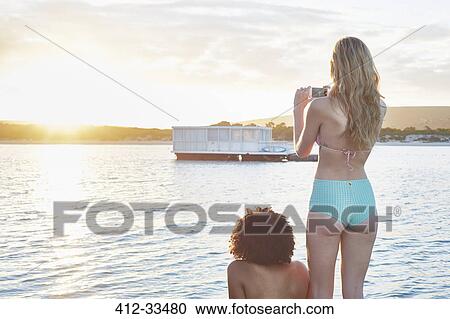 Young woman in bikini photographing houseboat on sunny summer ocean View Large Photo Image Stock Image - Young woman in bikini photographing houseboat on sunny summer ocean. Fotosearch