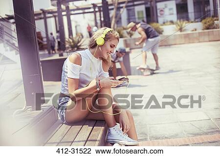 Stock Image - Young woman listening to music with headphones and mp3 player. Fotosearch