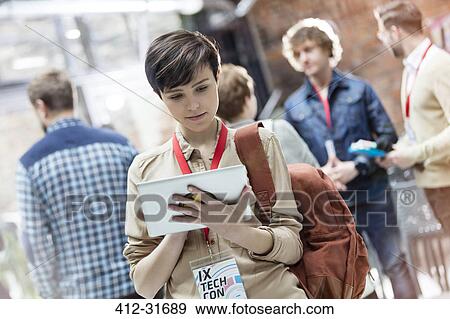 Stock Photo - Young woman using digital tablet at technology conference. Fotosearch