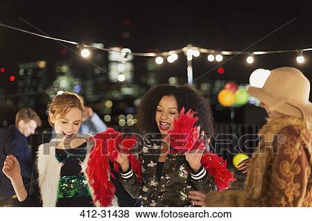 Young women dancing at rooftop party View Large Photo Image Stock Photo - Young women dancing at rooftop party. Fotosearch