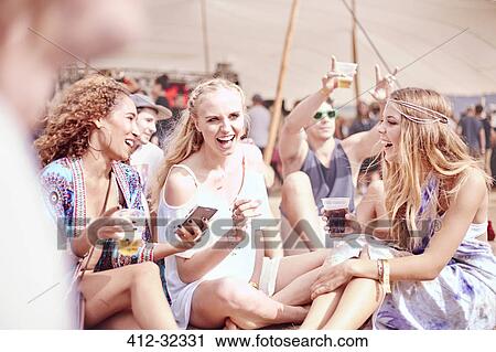 Young women hanging out drinking at sunny music festival View Large Photo Image Stock Image - Young women hanging out drinking at sunny music festival. Fotosearch