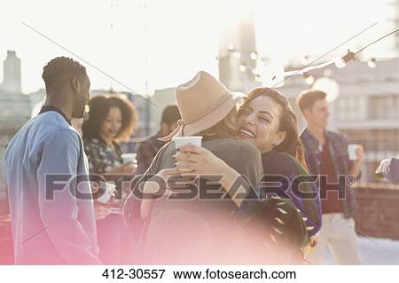 Young women hugging at rooftop party View Large Photo Image Stock Photo - Young women hugging at rooftop party. Fotosearch