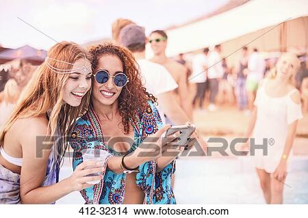 Picture - Young women posing for selfie at music festival. Fotosearch
