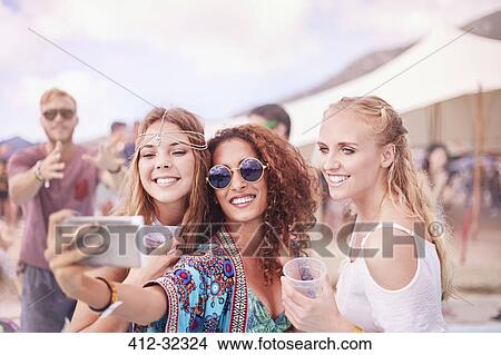 Picture - Young women posing for selfie at music festival. Fotosearch