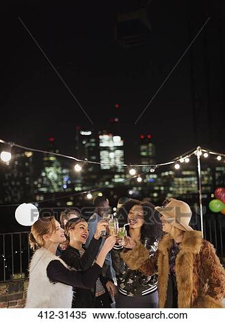 Young women toasting cocktails at nighttime rooftop party View Large Photo Image Stock Photography - Young women toasting cocktails at nighttime rooftop party. Fotosearch