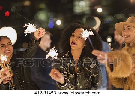 Young women waving sparklers at rooftop party View Large Photo Image Stock Image - Young women waving sparklers at rooftop party. Fotosearch