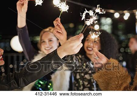 Young women waving sparklers at rooftop party View Large Photo Image Stock Photograph - Young women waving sparklers at rooftop party. Fotosearch
