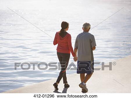 Older couple walking together on beach View Large Photo Image Stock Photograph - Older couple walking together on beach. Fotosearch