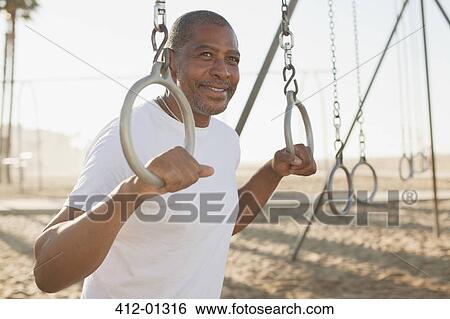 Older man holding exercise rings on beach View Large Photo Image Stock Photograph - Older man holding exercise rings on beach. Fotosearch