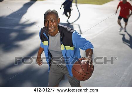 Stock Photo - Older man playing basketball on court. Fotosearch