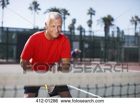 Stock Photograph - Older man playing tennis on court. Fotosearch