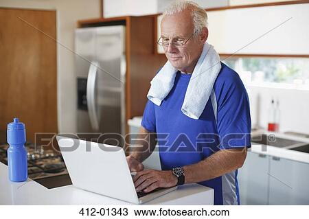 Stock Image - Older man using laptop after workout. Fotosearch