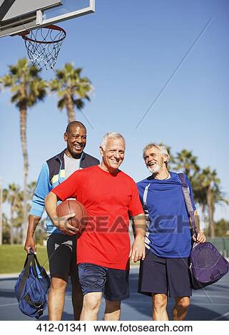 Stock Image - Older men playing basketball on court. Fotosearch