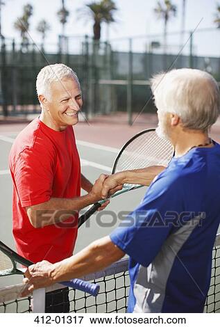 Older men shaking hands on tennis court View Large Photo Image Stock Photo - Older men shaking hands on tennis court. Fotosearch