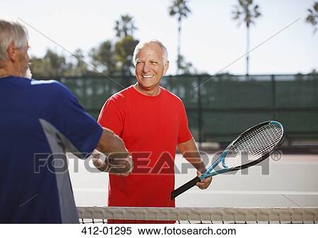 Stock Photography - Older men shaking hands on tennis court. Fotosearch