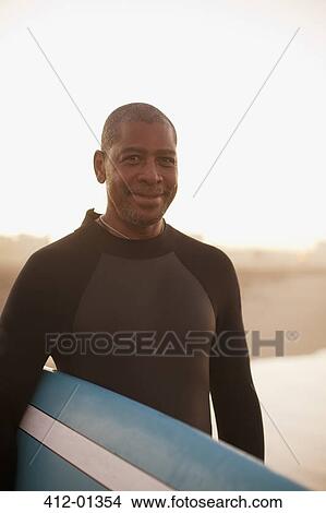 Older surfer carrying board on beach View Large Photo Image Picture - Older surfer carrying board on beach. Fotosearch