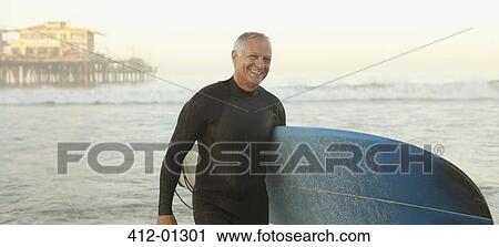 Older surfer carrying board on beach View Large Photo Image Stock Image - Older surfer carrying board on beach. Fotosearch