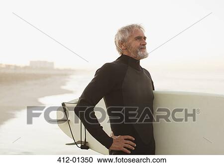 Older surfer carrying board on beach View Large Photo Image Stock Image - Older surfer carrying board on beach. Fotosearch