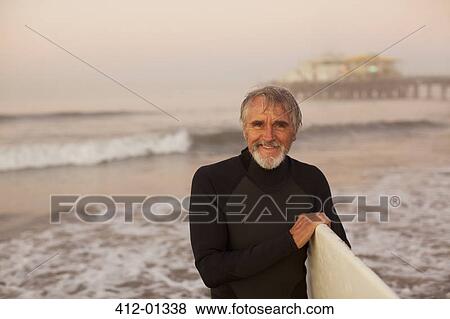 Older surfer carrying board on beach View Large Photo Image Stock Photo - Older surfer carrying board on beach. Fotosearch