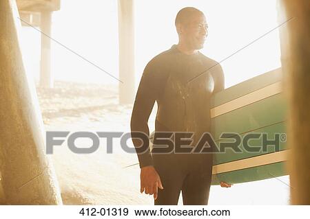 Older surfer carrying board under pier View Large Photo Image Stock Photo - Older surfer carrying board under pier. Fotosearch