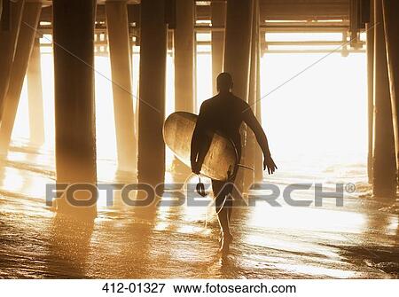 Older surfer carrying board under pier View Large Photo Image Stock Photo - Older surfer carrying board under pier. Fotosearch