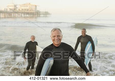 Older surfers carrying boards on beach View Large Photo Image Stock Image - Older surfers carrying boards on beach. Fotosearch