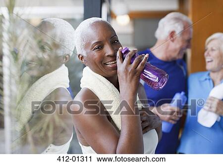 Stock Image - Older woman drinking water after workout. Fotosearch