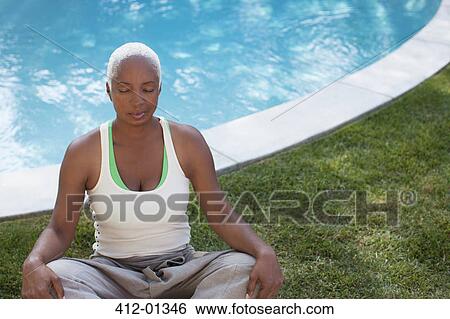 Stock Photograph - Older woman meditating in backyard. Fotosearch
