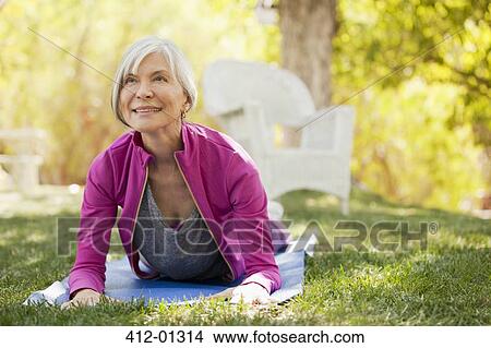 Picture - Older woman practicing yoga in backyard. Fotosearch