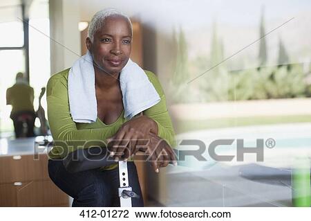 Older woman sitting on exercise bike in home View Large Photo Image Stock Image - Older woman sitting on exercise bike in home. Fotosearch