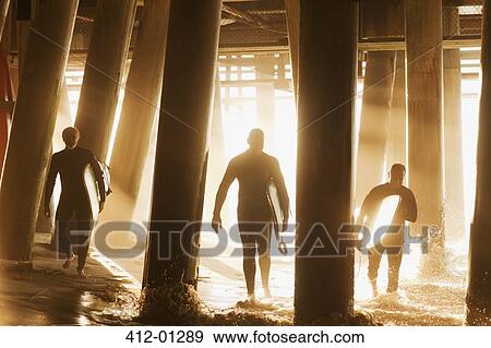 Surfers carrying boards under pier View Large Photo Image Stock Photo - Surfers carrying boards under pier. Fotosearch