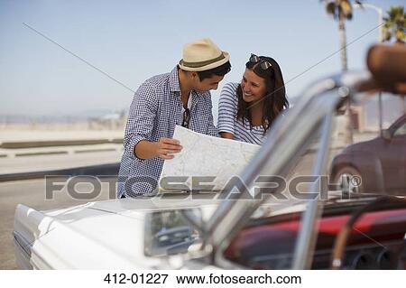 Couple reading road map on convertible View Large Photo Image Stock Photo - Couple reading road map on convertible. Fotosearch