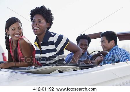 Stock Image - Friends sitting in convertible together. Fotosearch