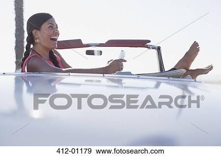 Laughing girl using cell phone in convertible View Large Photo Image Stock Photo - Laughing girl using cell phone in convertible. Fotosearch