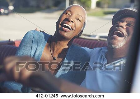 Stock Photography - Older couple laughing in convertible. Fotosearch