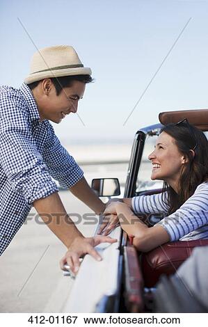 Stock Photo - Smiling couple talking in convertible. Fotosearch